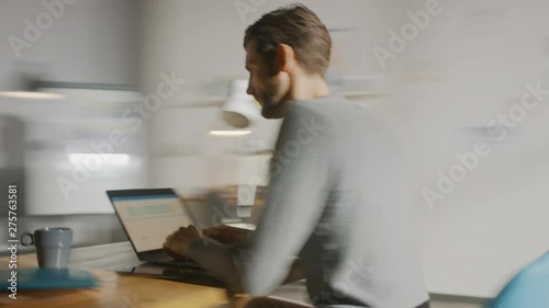 Professional Creative Man Sitting at His Desk in Home Office Studio Working on a Laptop Writes down Notes. Energetic Fast Paced Time-Lapse Fast forward Movement. 360 Degree Tracking Arc Shot