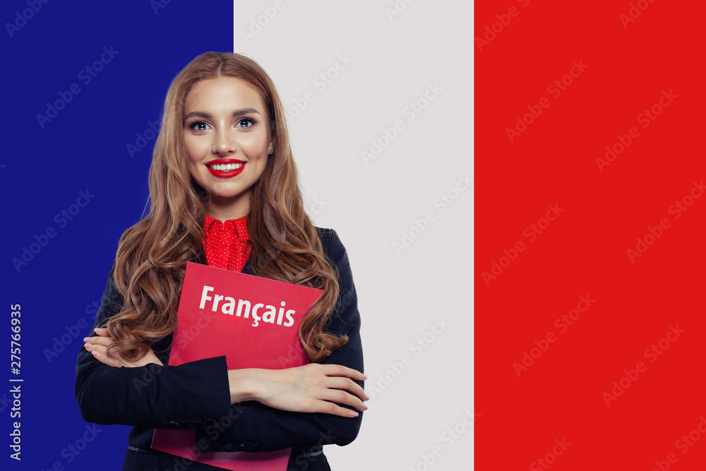 Portrait of pretty young smiling woman with book on the French flag background. Travel in France and study in French language school - obrazy, fototapety, plakaty 