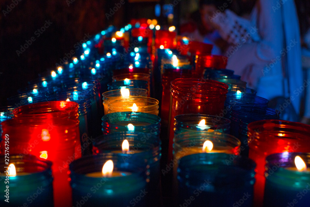Closeup of colorful candles burning in the tunnel of Covadonga, Cangas de Onis, Asturias, Spain. Spirituality.