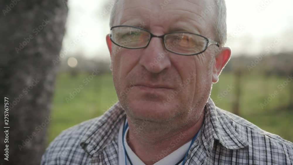 Face serious young farmer with glasses look at camera sunset standing at field of organic farm agricultural farm male man nature worker adult countryside face businessman slow motion Face serious young farmer with glasses look at camera sunset standing at field of organic farm agricultural farm male man nature worker adult countryside face businessman slow motion