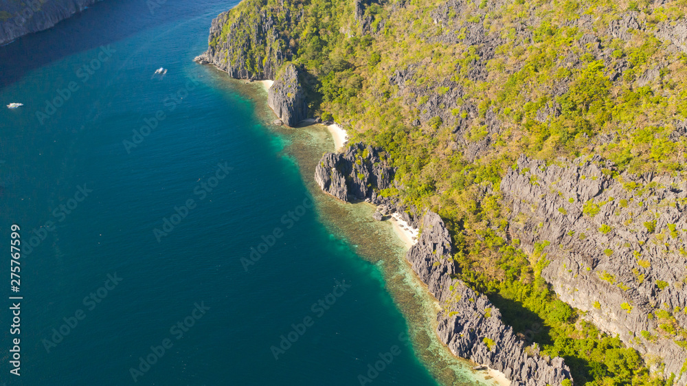 Rocky coast with a white beach. Tropical island with jungle. El Nido Palawan National Park Philippines. White sand beach and turquoise lagoon.