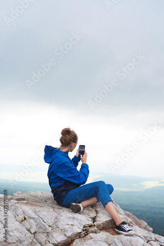 Tourist woman taking photo of scenic view on top of the hill