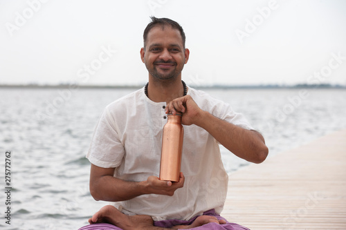 Man doing yoga on a wooden floor in the nature. Fresh water conservation concept.