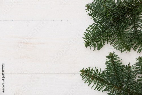 Top view of the fir branches lying on a white wooden table. Christmas mood. Copy space. New Year or holiday concept