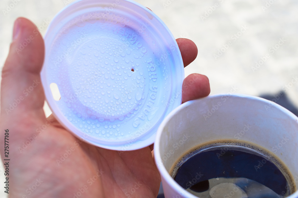 Coffee-to-Go Becher mit Deck und Hand in einer Stadt Coffee-to-Go Becher mit Deck und Hand in einer Stadt