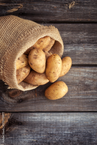 Raw potato food . Fresh potatoes in an old sack on wooden background