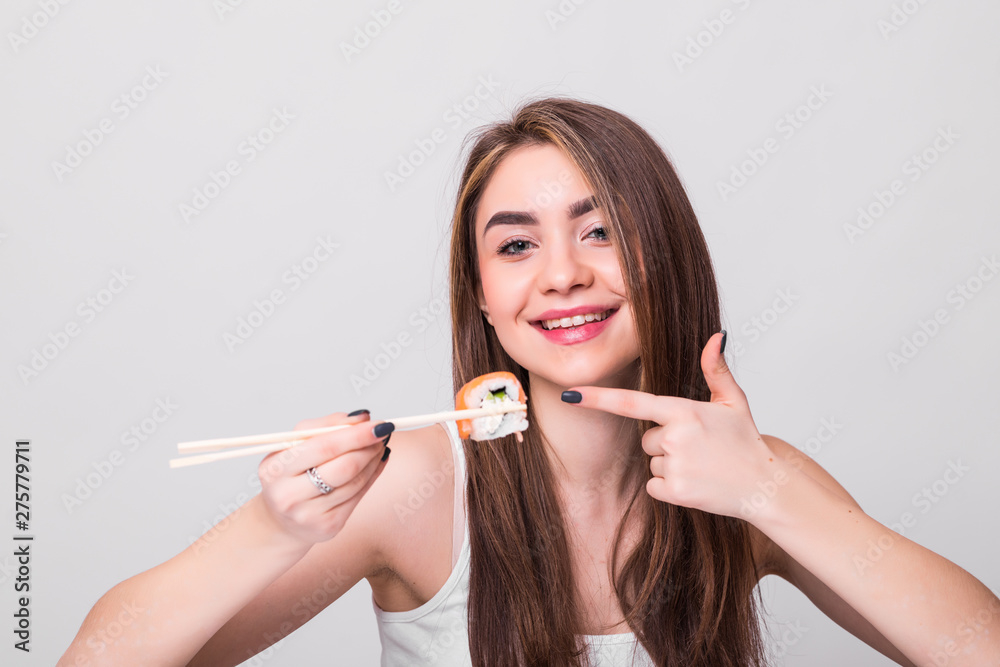 Young attractive woman holding sushi with a chopsticks on white background Young attractive woman holding sushi with a chopsticks on white background