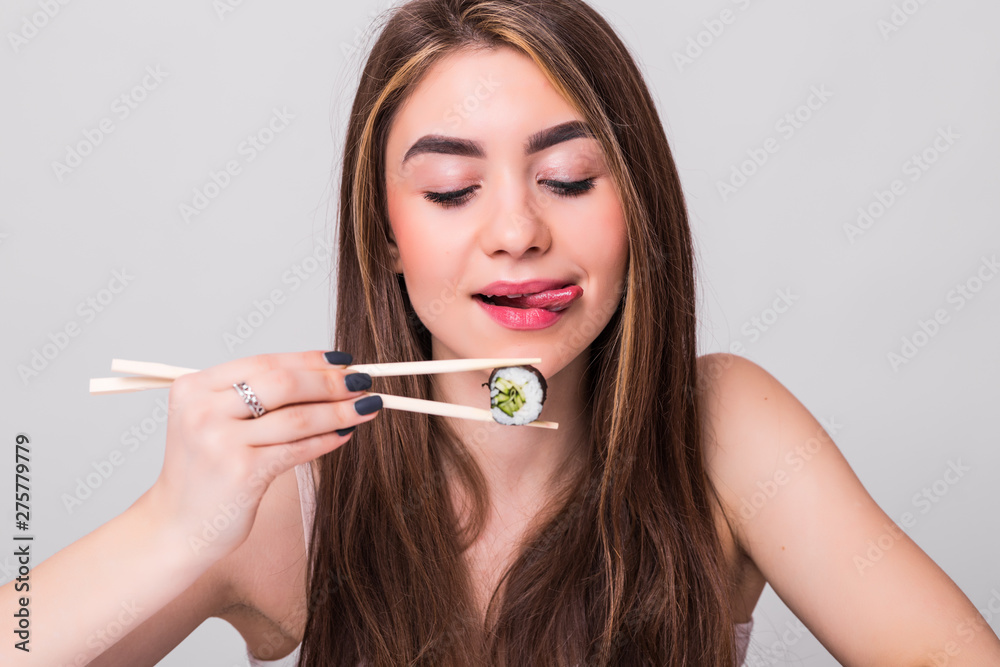 Young pretty woman holding sushi with a chopsticks, isolated on white background Young pretty woman holding sushi with a chopsticks, isolated on white background