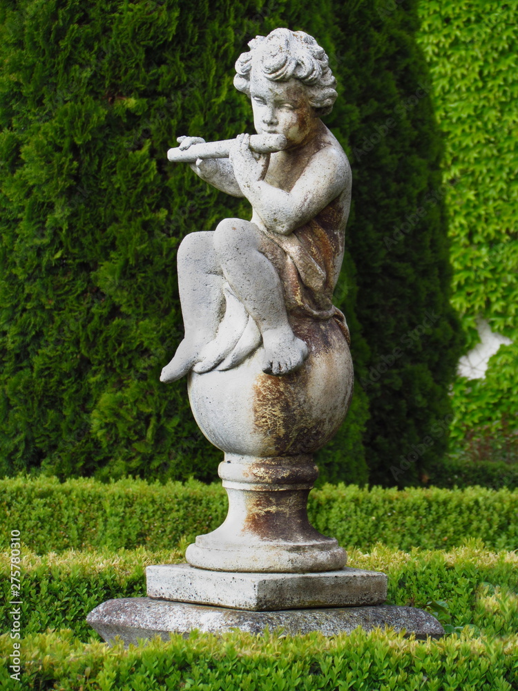 baroque statue in castle park, little boy playing the flute, white sculpture