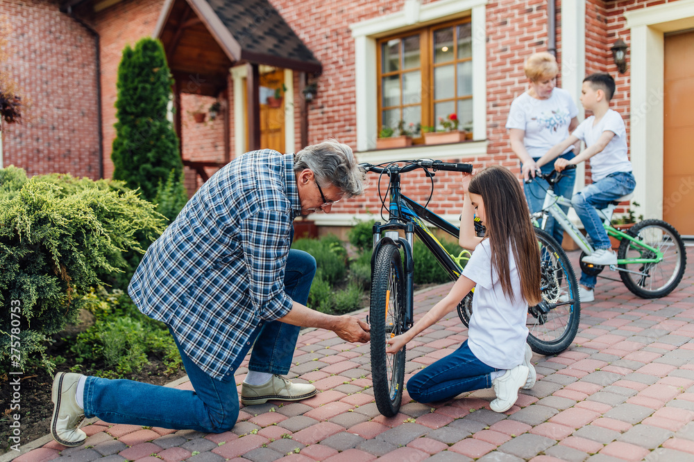 Bike repair.Older man repairing bike for his children. Home time, resting concept. Bike repair.Older man repairing bike for his children. Home time, resting concept.