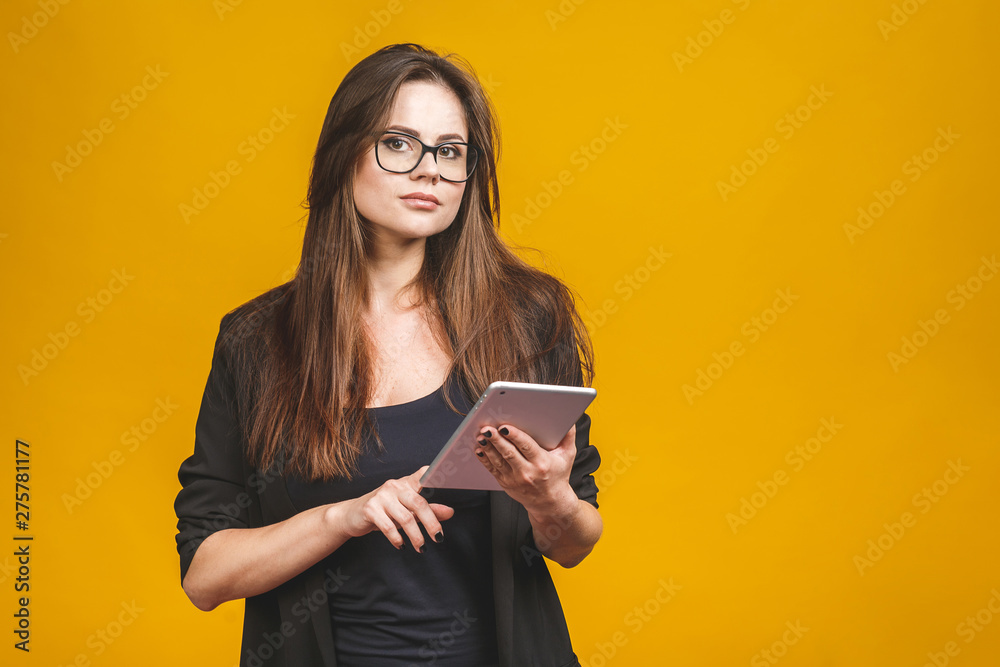 Business woman holding tablet computer isolated against yellow background. Business woman holding tablet computer isolated against yellow background.
