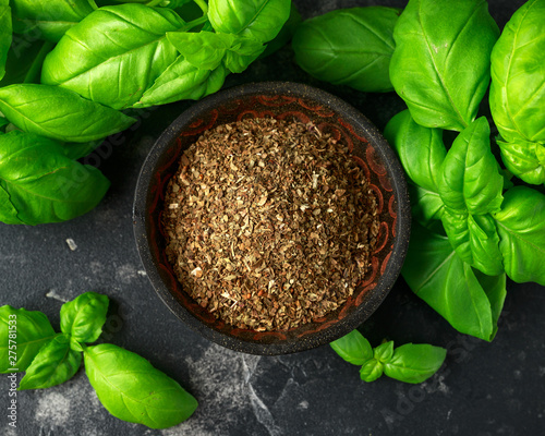 Fresh and dried basil in bowl. on black rustic table