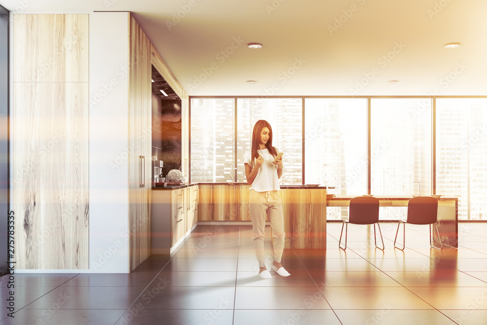 Fototapeta premium Woman with phone in wooden kitchen with table