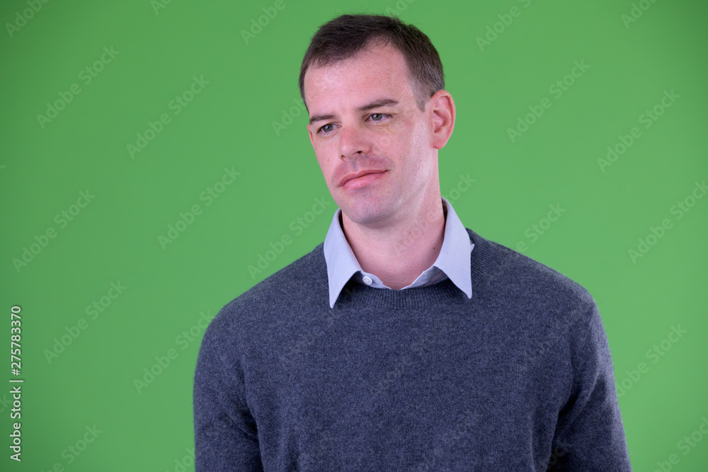 Fototapeta premium Face of businessman thinking against green background
