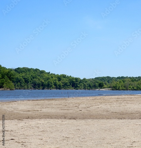 A view of the lake from the sandy beach on a sunny day.