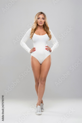 Young, fit and sexy girl in white swimsuit. Beautiful woman posing in studio.