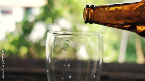 Slow Motion of Young Person Pouring Beer from Bottle into a Glass at the Backyard. POV Shot