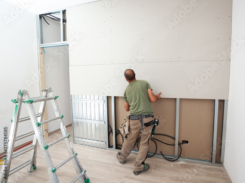 Worker building plasterboard wall. photo