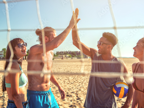 Schilderij op canvas Group of friends playing at beach volley at the beach