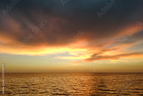 a beautiful sunset at varakkal beach with dark shining colouds ocean coast reflection on the sea making a nature art horizon © deebhesh