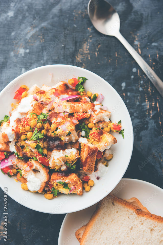 Bread chaat/chat is a yummy starter/appetizer from India, served in a bowl garnished with tomato, sev and coriander and masala. selective focus
