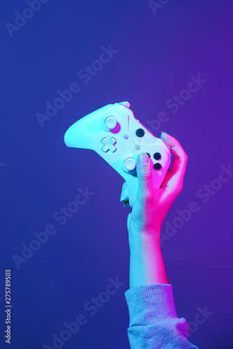Canvas-taulu Hand with white gamepad on dark violet background.