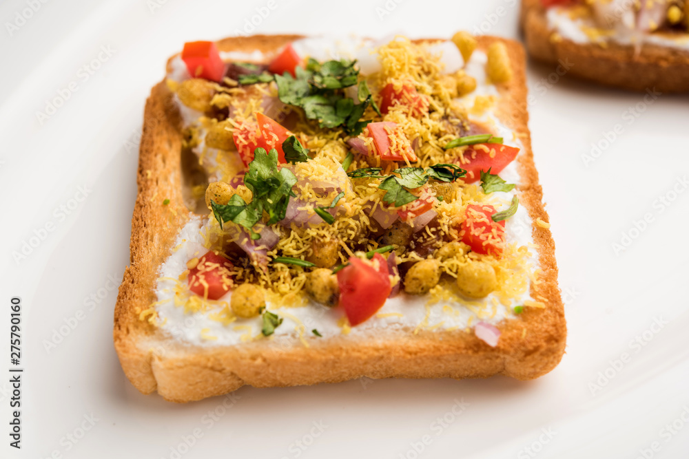Bread ppadi chaat/chat is a yummy starter/appetizer from India, served in a plate garnished with tomato, sev and coriander and masala. selective focus