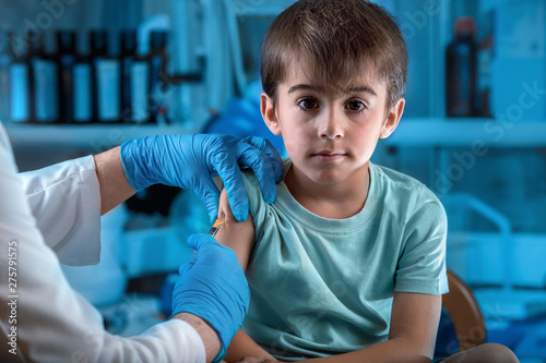 doctor injecting vaccine preventive to little boy in the hospital photo