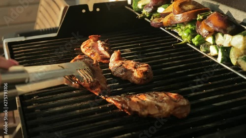 Close-up shot of cooking grilled chicken in baarbecue. Chef turns the meat in the grill.
