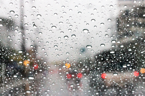 The windshield has rain water on the road when driving on the city streets.