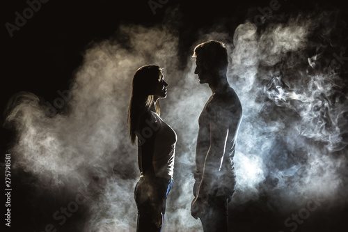 The couple standing in smoke on the dark background