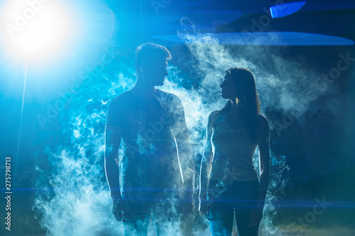 The man and woman standing in the smoke on a bright light background