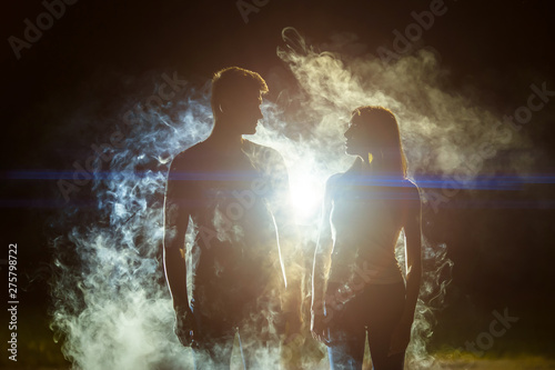 The couple standing in the smoke on a bright light background
