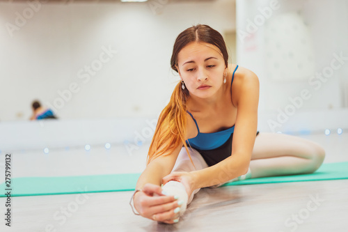 the girl is engaged in gymnastics , doing stretching in the gym