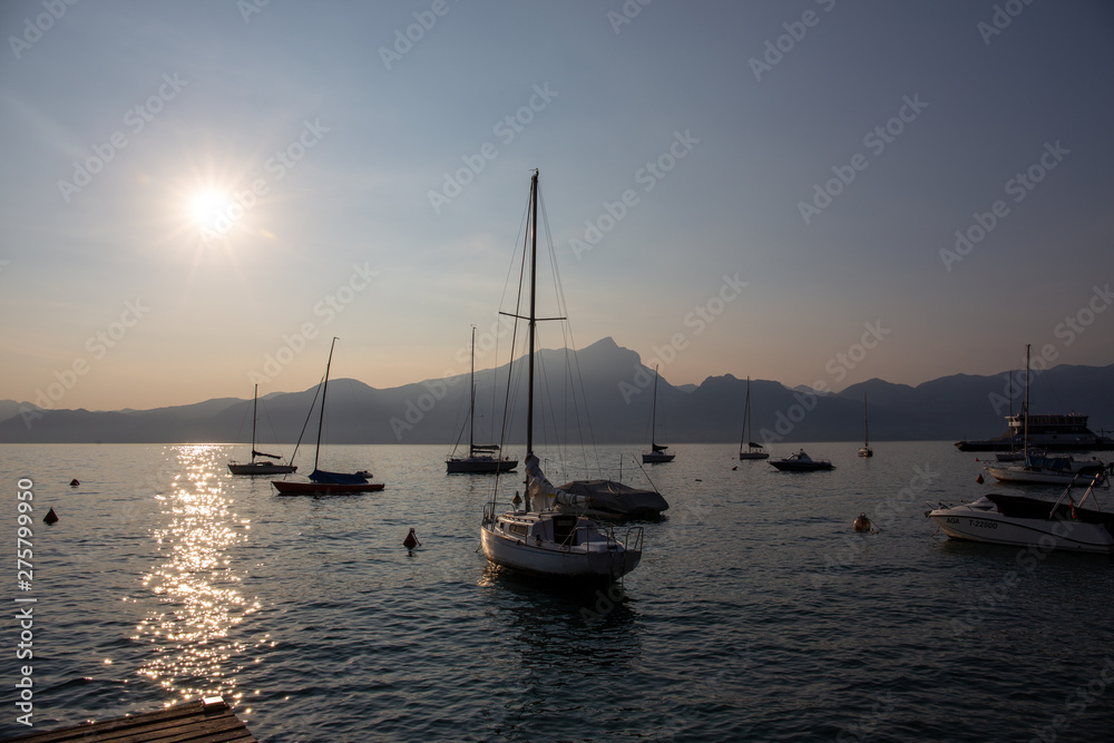 Boats docked in the Garda Lake at sunset, in the Torri Del Benaco town port; almost sunset, beautiful light