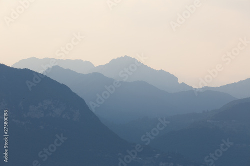 Natural patterns: layers of mountains in a foggy soft light at sunset. Garda Lake, Italy. Artistic, almost abstract © laura