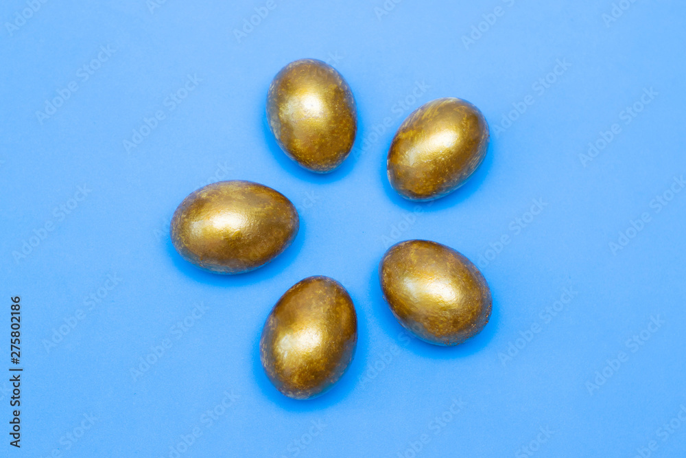 Golden eggs on a blue background. Concept of wealth