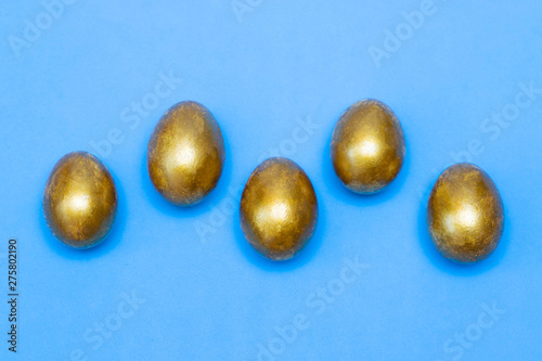 Golden eggs on a blue background. Concept of wealth