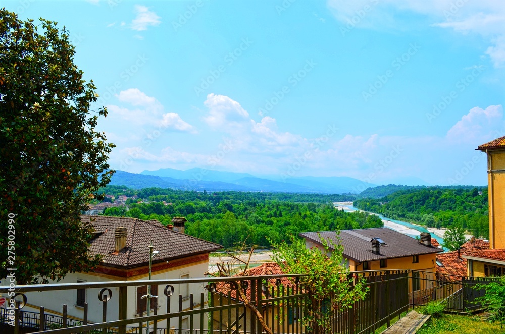 panoramic view of mountains and forests with houses and railings in the foreground