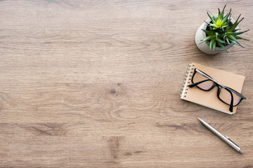 Wood office desk table with notebook, pen and supplies. Top view with copy space, flat lay.