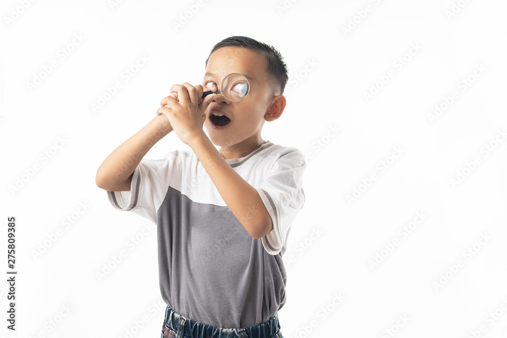 Young Asian boy use magnifying glass, Thai student isolated on white background