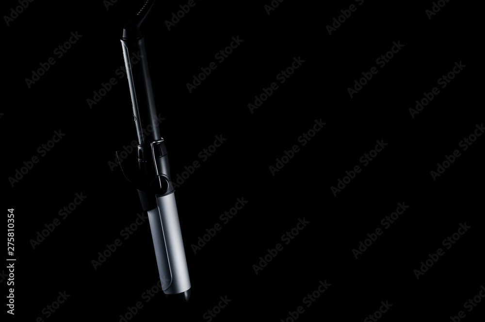 Naklejka premium Modern beautiful curling iron for hair styling on a black background, isolate. Tool for creating hairstyles.
