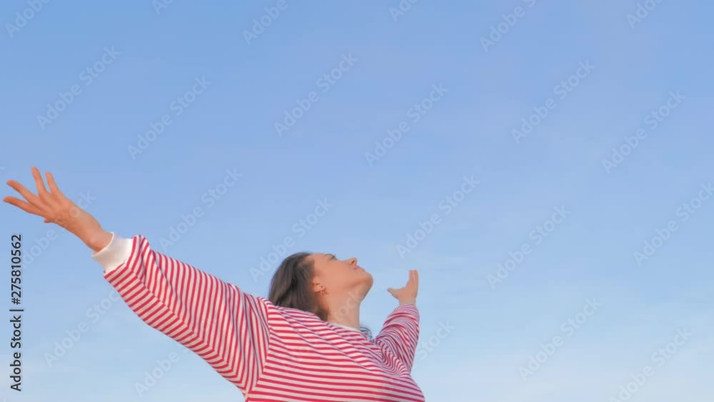 Woman raising arms to the sky. Happy female feeling the breeze on sky background Woman raising arms to the sky. Happy female feeling the breeze on sky background