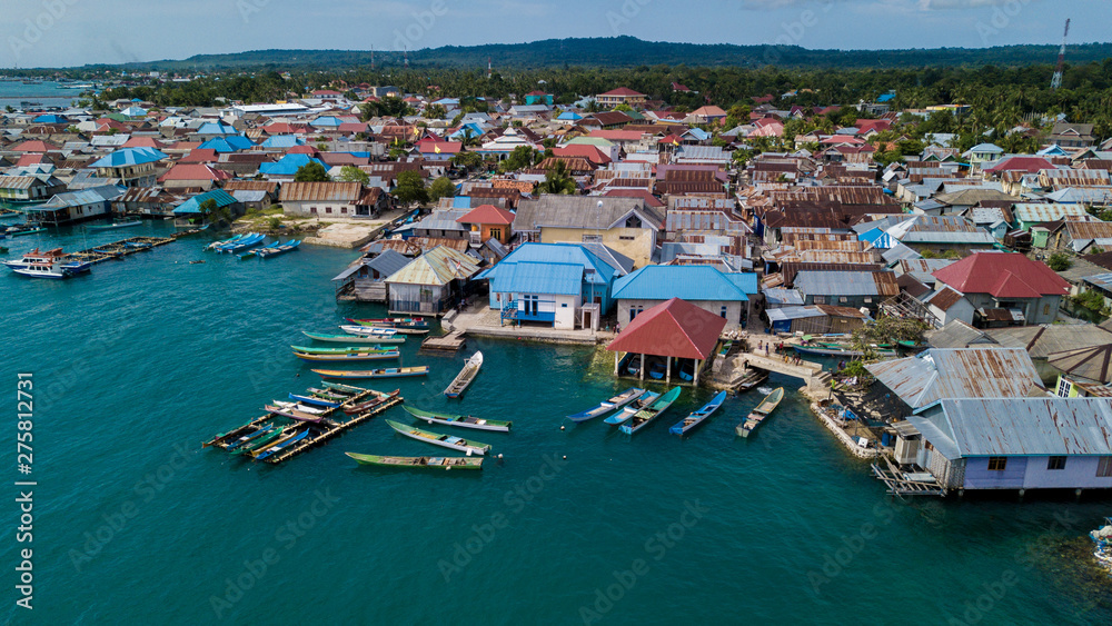 Beautiful aerial views of the village near the sea against the background of hills and forests along with many wooden boats lined up near the village