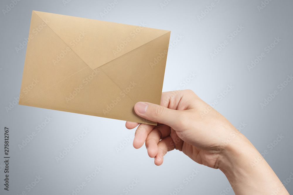 Hand giving a brown envelope on gray background