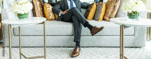 richness and success concept. business man sitting on a leather couch, putting his foot on the leg