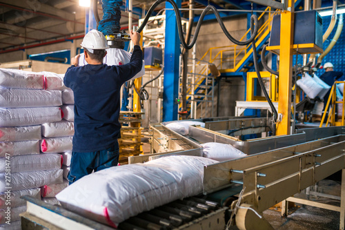 Worker loading Rows or stacks of white sack bags at large warehouse in modern factory. Packacing in factory or warehouse