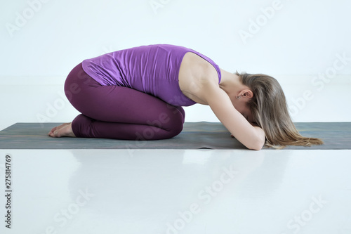 Caucasian woman practices yoga asana balasana or child pose, restorative pose after hard asana.