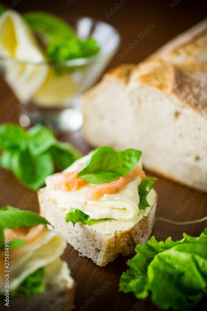 sandwich with cheese, salad leaves and red fish on a wooden