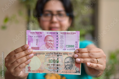 A girl holding old 1000 and new 2000 denomination Indian Rupees Currency note with hands stretched after demonetisation photo